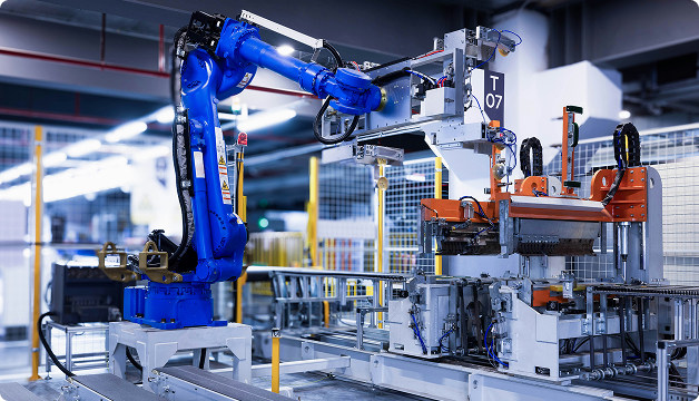 Blue industrial robotic arm operating automated machinery in a manufacturing facility.