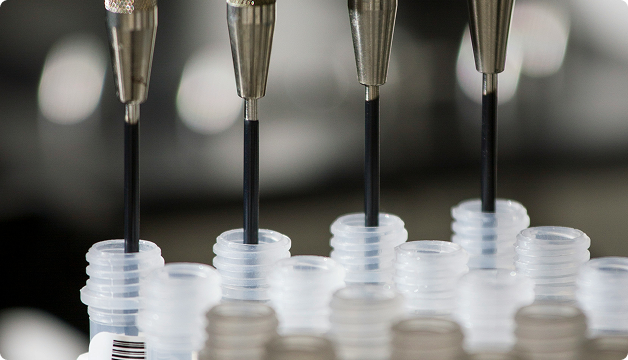 Automated pipettes dispensing liquid into small laboratory sample tubes.