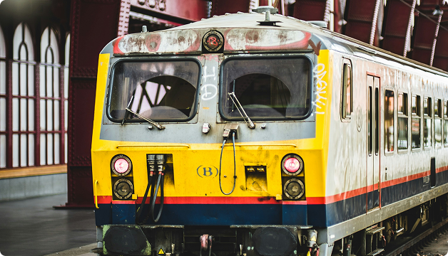 Yellow and white passenger train with a red lower stripe at a railway station.